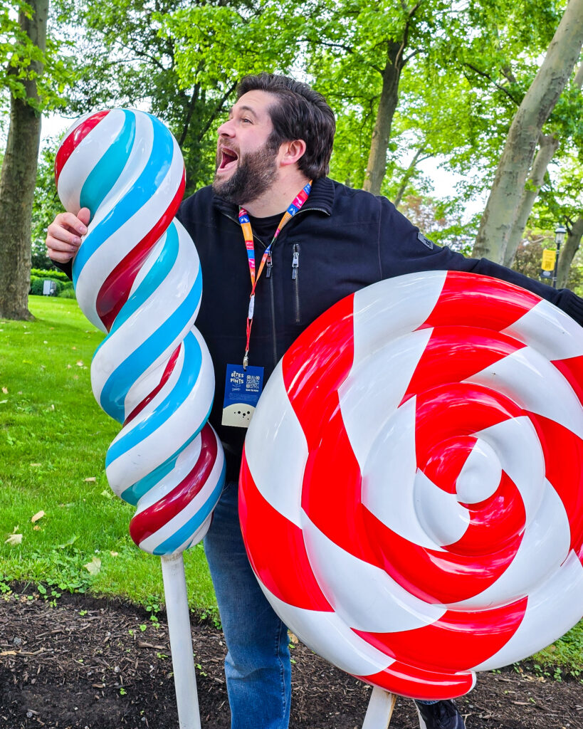 Alex at Kennywood park pretending to eat the giant fake lollipops at the entrance