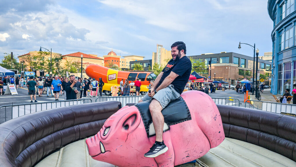 Alex riding a mechanical hog at BaconBurgh