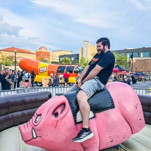 Alex riding a mechanical hog at BaconBurgh
