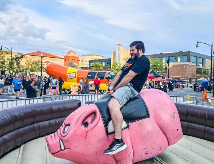Alex riding a mechanical hog at BaconBurgh