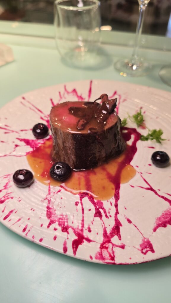 venison tenderloin cooked medium rare with blueberry sauce served at Test Kitchen on Virgin Voyages Scarlet Lady cruise ship