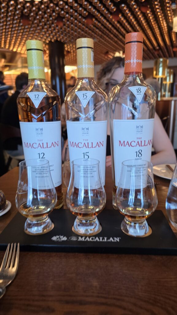 Macallan Scotch flight of 12, 15, and 18 Year-old scotches in glencairn glasses with the bottles behind served at The Wake on Virgin Voyages Scarlet Lady cruise ship