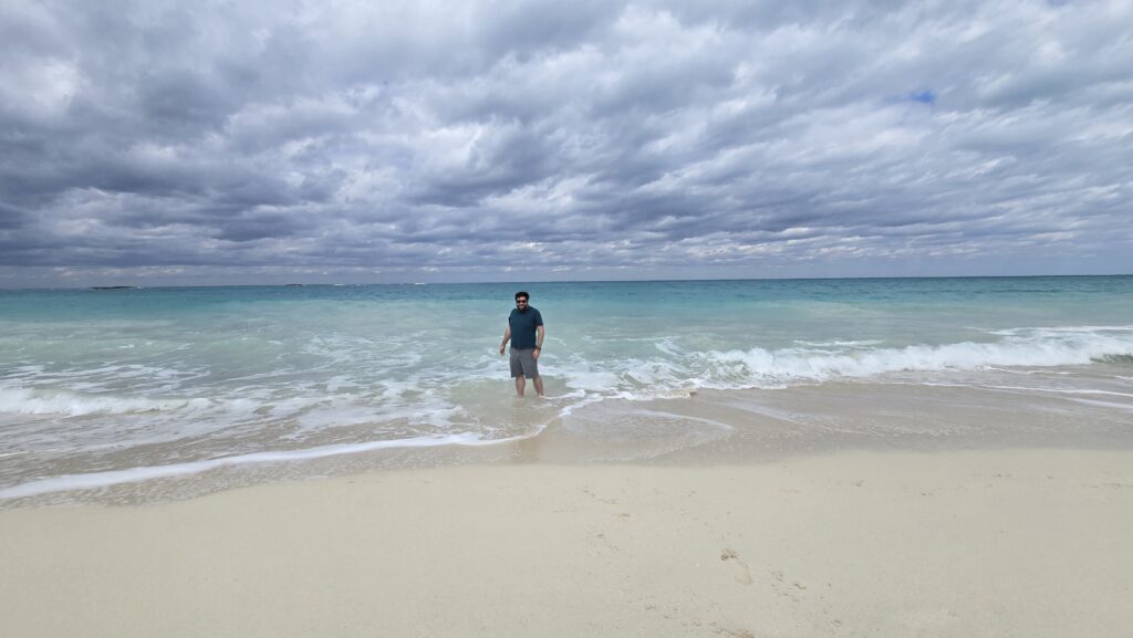 Alex standing in the water at the beach at the Virgin Voyages Bimini Beach Club in the Bahamas