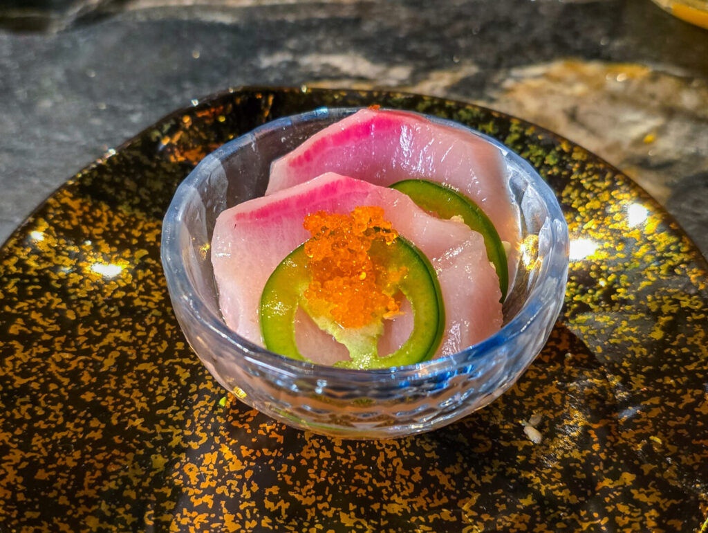 small bowl of yellowtail tuna sashimi with jalapeño pepper slices and orange salmon fish row on top