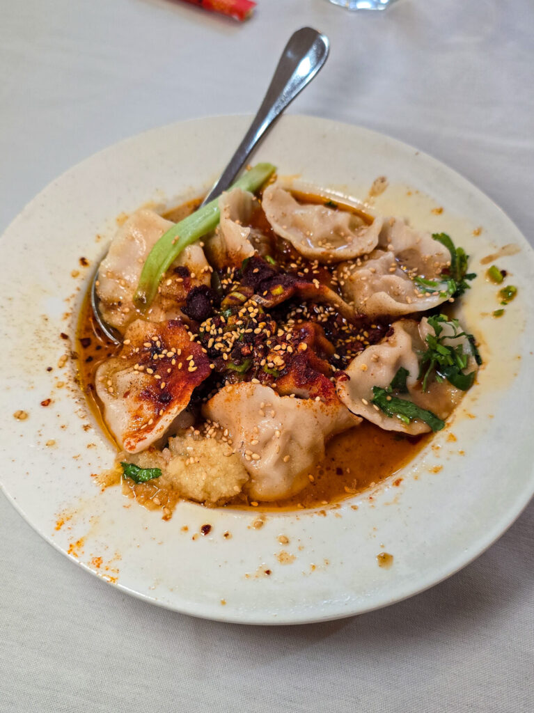 a bowl of chinese dumplings covered in oil chili pepper oil